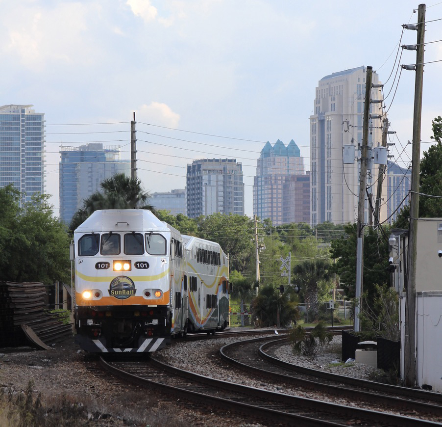 Commuter train rounds curve with city skyline in background