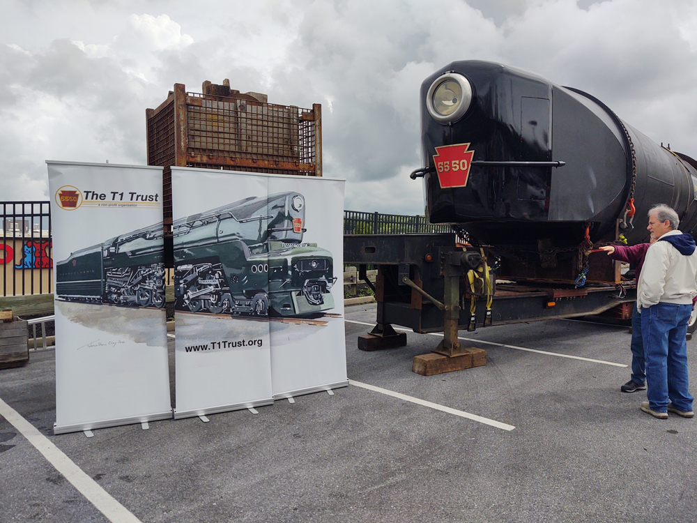 Front of locomotive being built next to banner with picture of complete engine