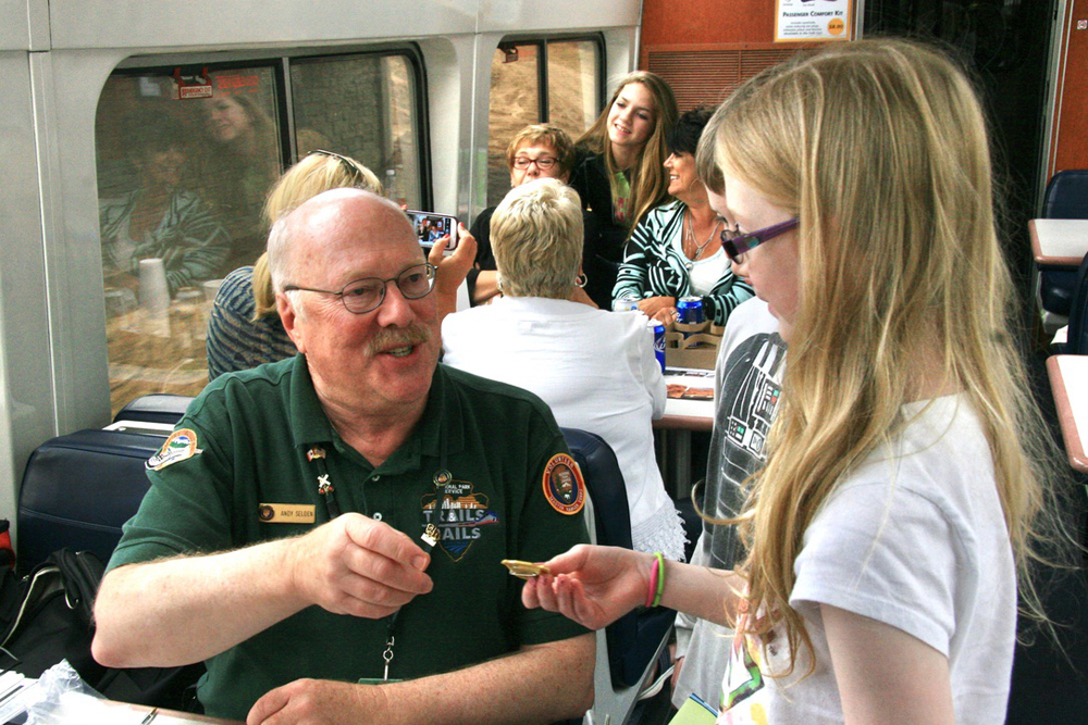 Man with glasses handing small object to pre-teen girl