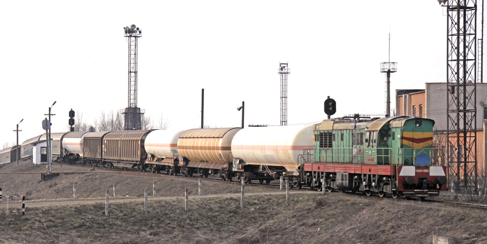 Green and red European diesel locomotive with cars at hump yard