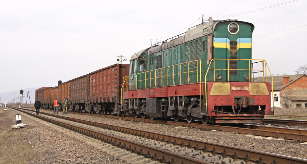 Green and red locomotive with a small number of freight cars