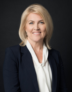 Woman in black coat and white blouse against black background