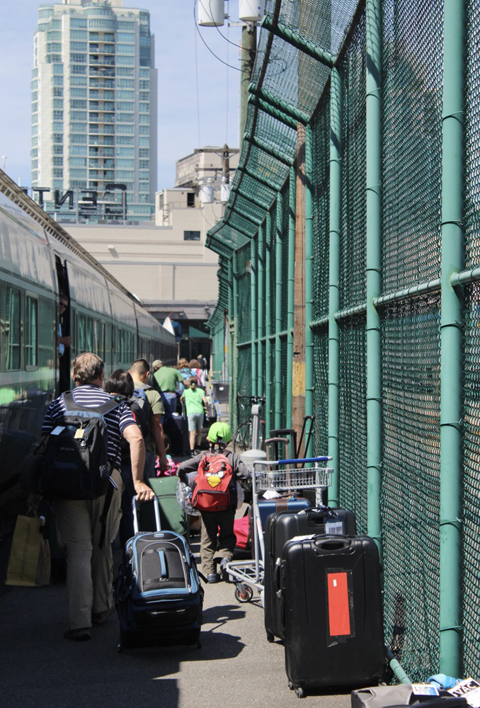 People and luggage on fenced-off station platform