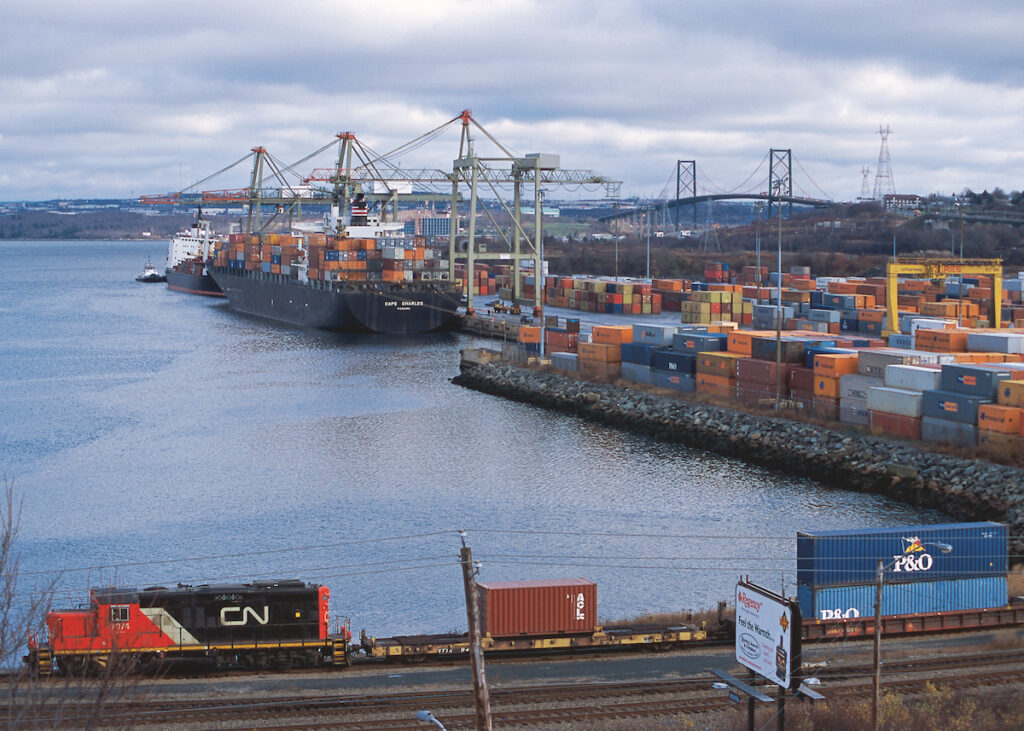 Locomotive moving cars of containers with ship and dock in background