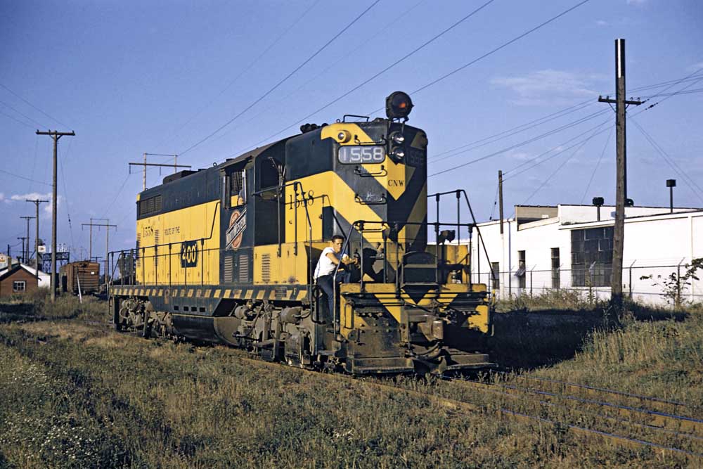 Yellow and green diesel locomotive among industrial building
