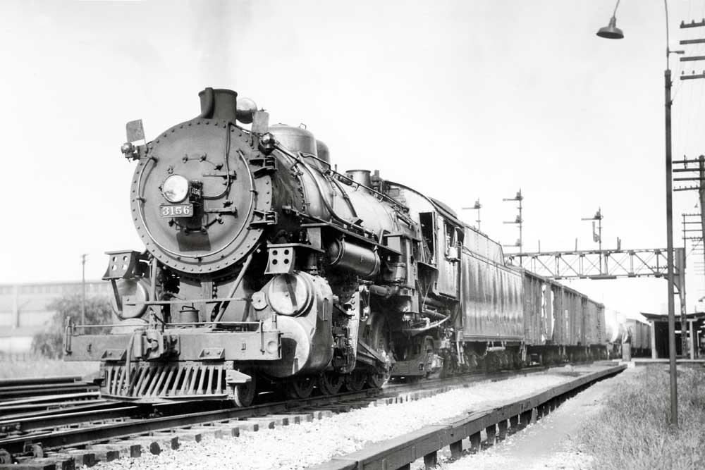Steam locomotive with train under signal bridge