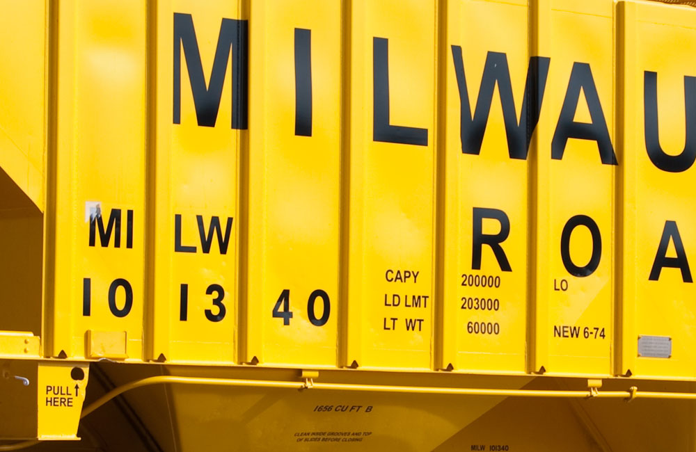 Freight car lettering: A close-up of lettering on the side of a bright yellow Milwaukee Road covered hopper