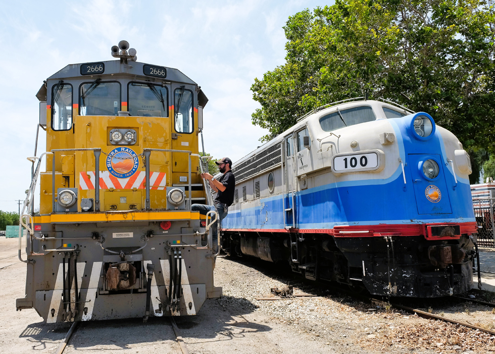 Man climbing ladder onto locomotive deck.
