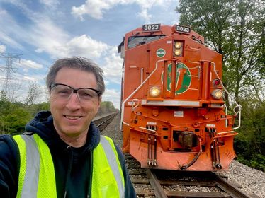 Man with safety gear near a locomotive.