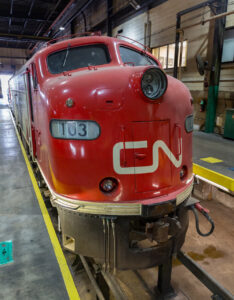 Locomotives with two diesel engines: A red cab unit locomotive in a shop building.