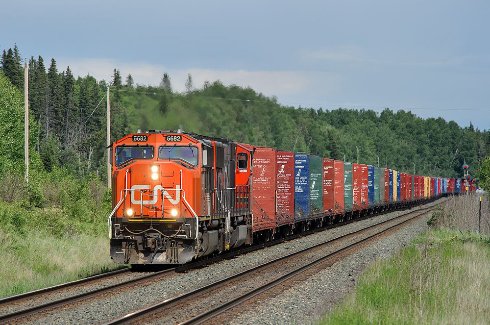 Red and black locomotive with empty bulkhead flatcars