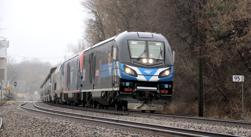 Black locomotive with blue and white stripes leads passenger train