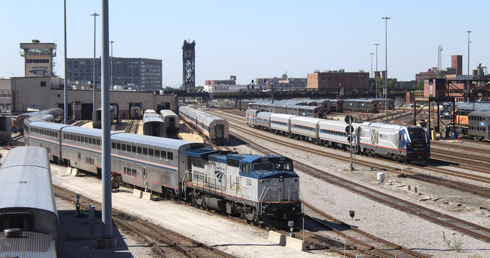 Locomotive switches passenger cars in foreground as train passes in background