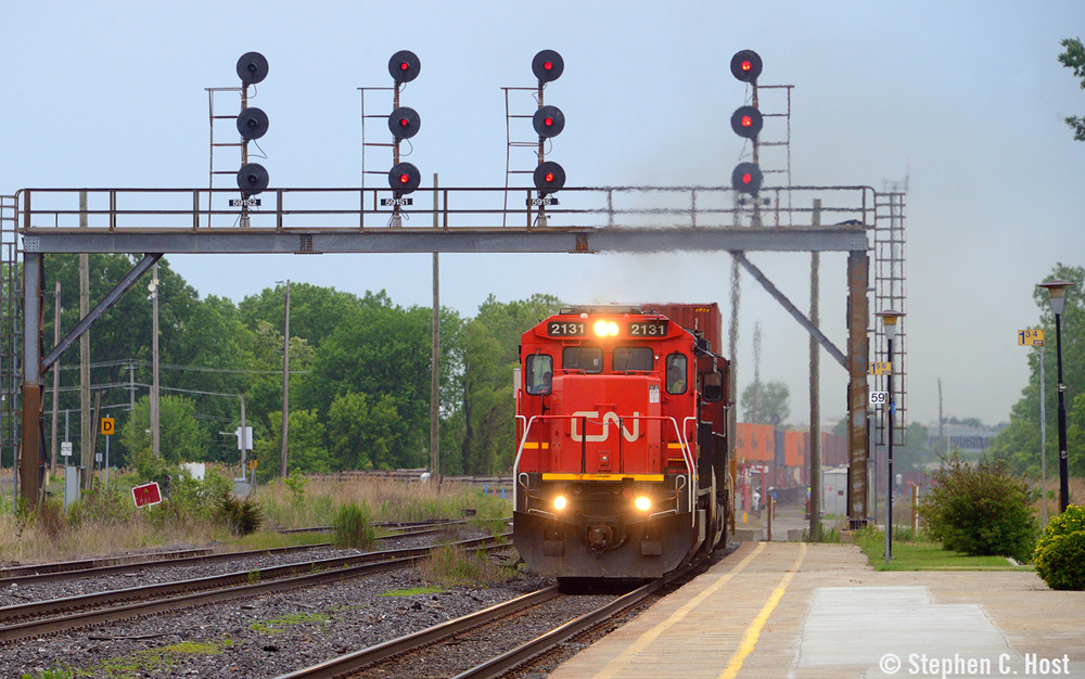 Locomotive with red nose passes under signal bridge