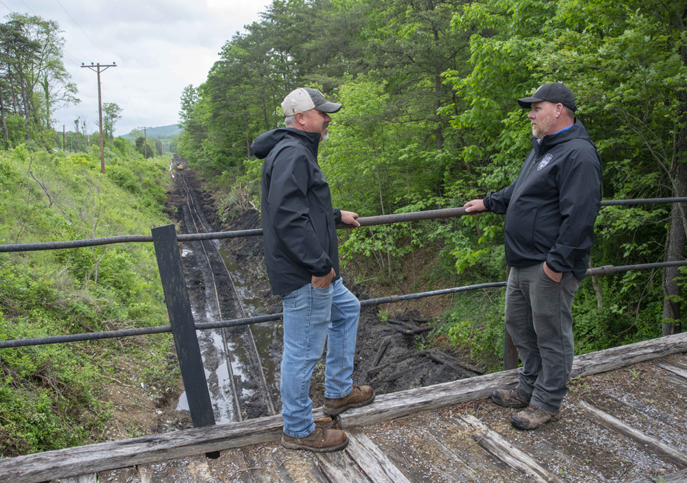 Two men talking on bridge with work on rail line in background