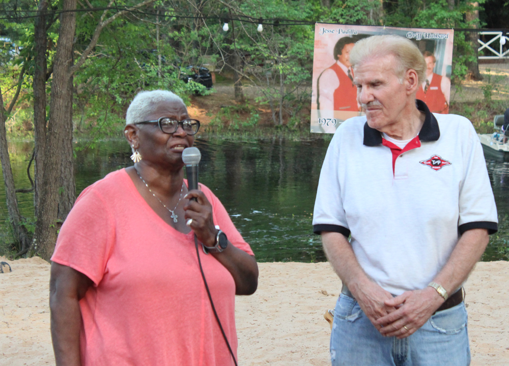 Woman speaking into microphone as man next to her looks on