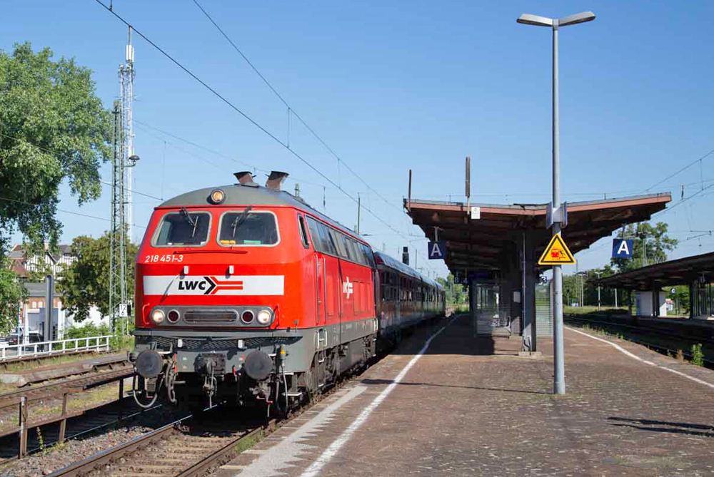 Red older diesel locomotive on passenger train at station