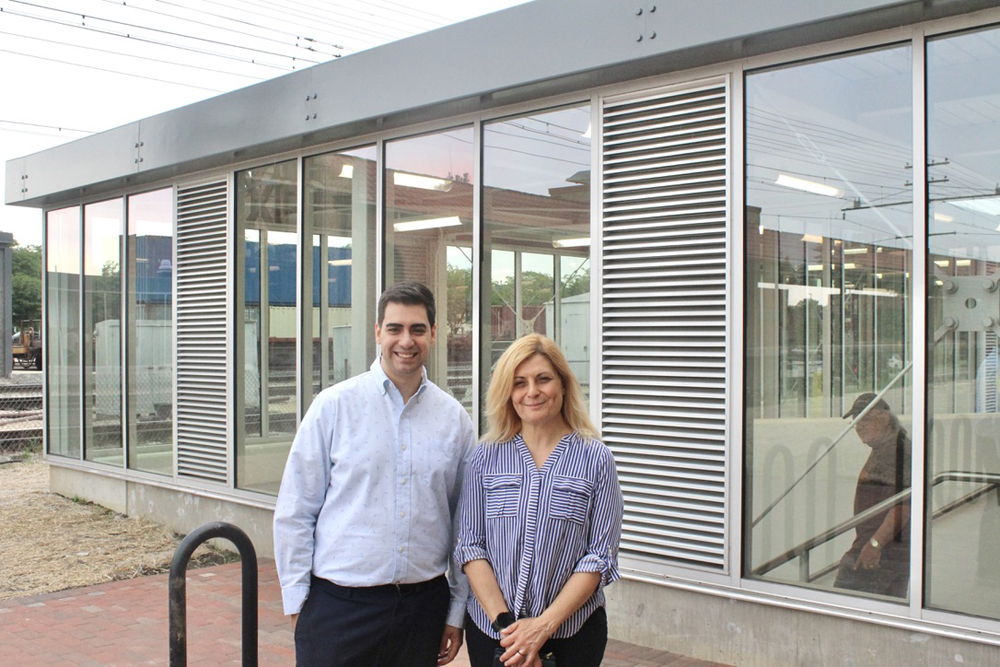 Two people standing outside building with large glass windows