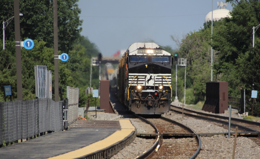 Train with black locomotive approaches curve at commuter rail station