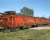 Red and maroon gas motorcar with trailer in front of station