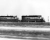 Black and white diesel locomotives race traffic along a highway