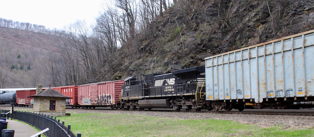 Diesel locomotive tucked between freight train while going around a curve.