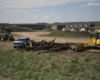 Wood debris with tractors, pickups, and new apartments in scene