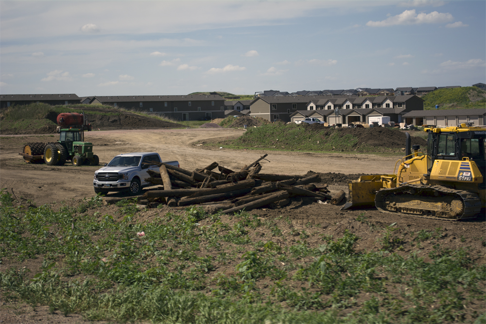 Wood debris with tractors, pickups, and new apartments in scene