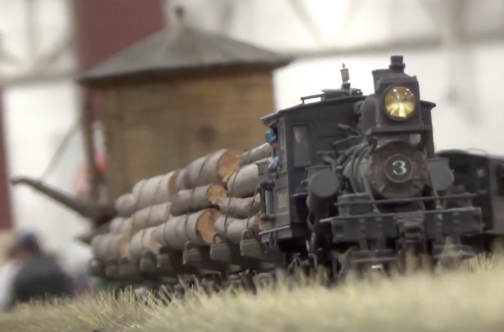 HO-scale model of a logging locomotive hauling a train in a prairie scene.