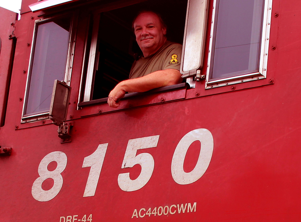 man inside red diesel locomotive cab