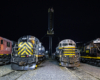 Four locomotives lined up side-by-side in a nighttime photo event.
