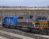 Yellow, blue, and gray-and-black diesel locomotives in a rail yard.