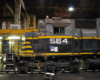 Close side-view of a black and gray diesel locomotive in a shop at night.