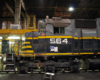 Close side-view of a black and gray diesel locomotive in a shop at night.