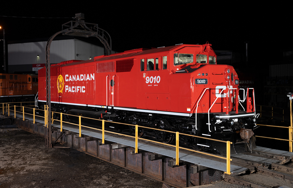 A bright red locomotive appears well-lit in a nighttime photograph.
