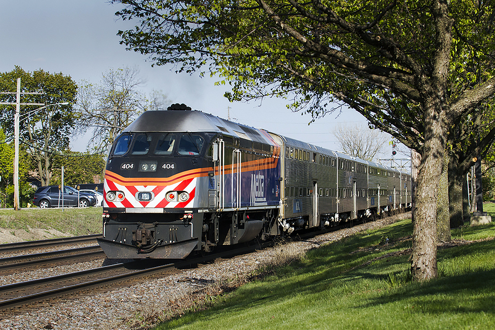 A three-quarter wedge image of a passenger train in a landscape suburban area.