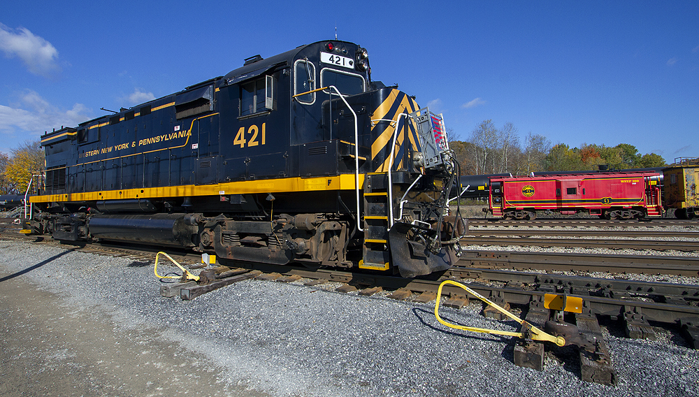 Close-up image of a black-and-yellow locomotive with a caboose in the background.