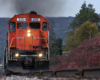 Low-angled, tight image of a red locomotive leading a train.