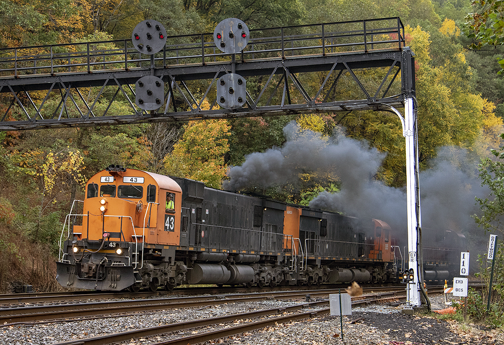 Two smoking locomotives lead a train underneath old color position signals.