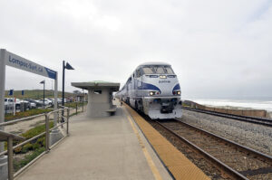 A passenger train at a mostly deserted station on a cloudy day.