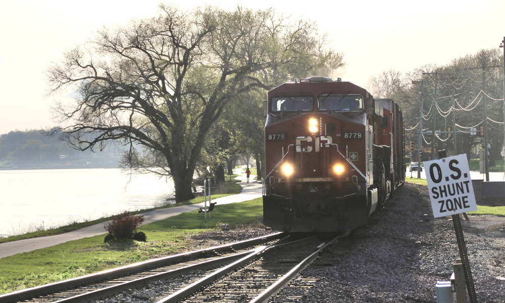 Train with red locomotive next to river