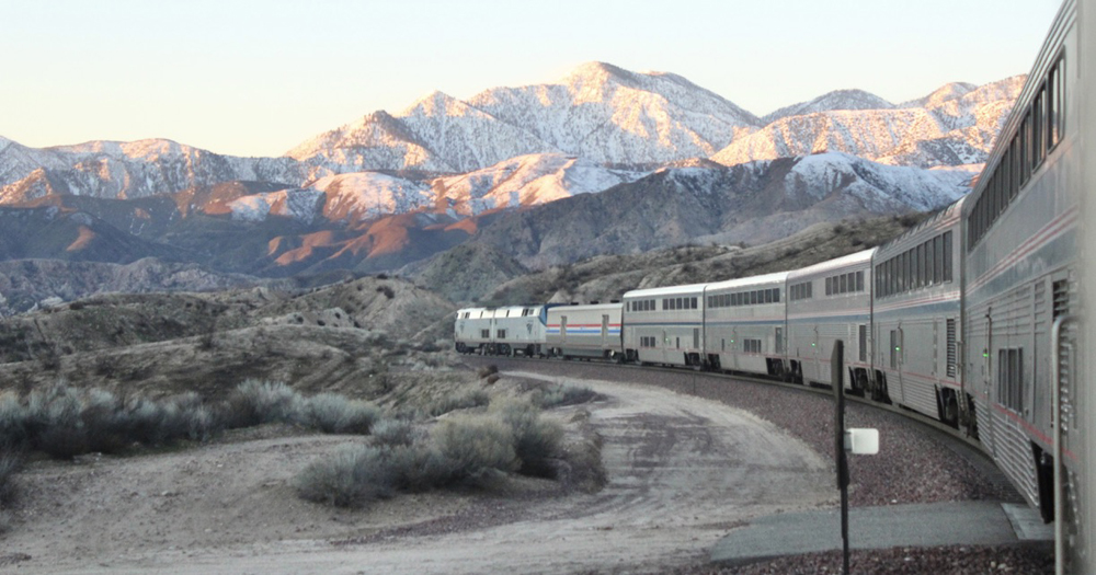 Passenger train seen from onboard with snow-capped mountains in distance