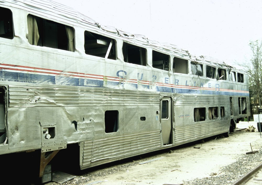 Bilevel passenger car with no windows and damage to stainless steel body