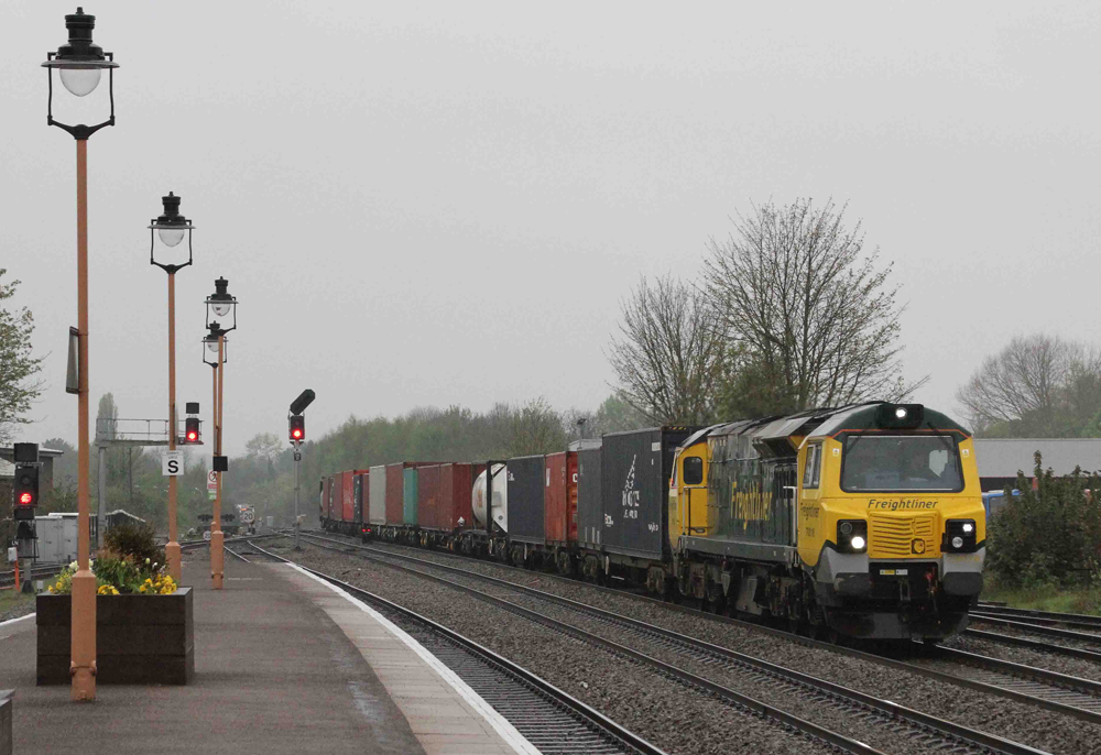 Yellow and blue freight locomotive with train passing passenger station