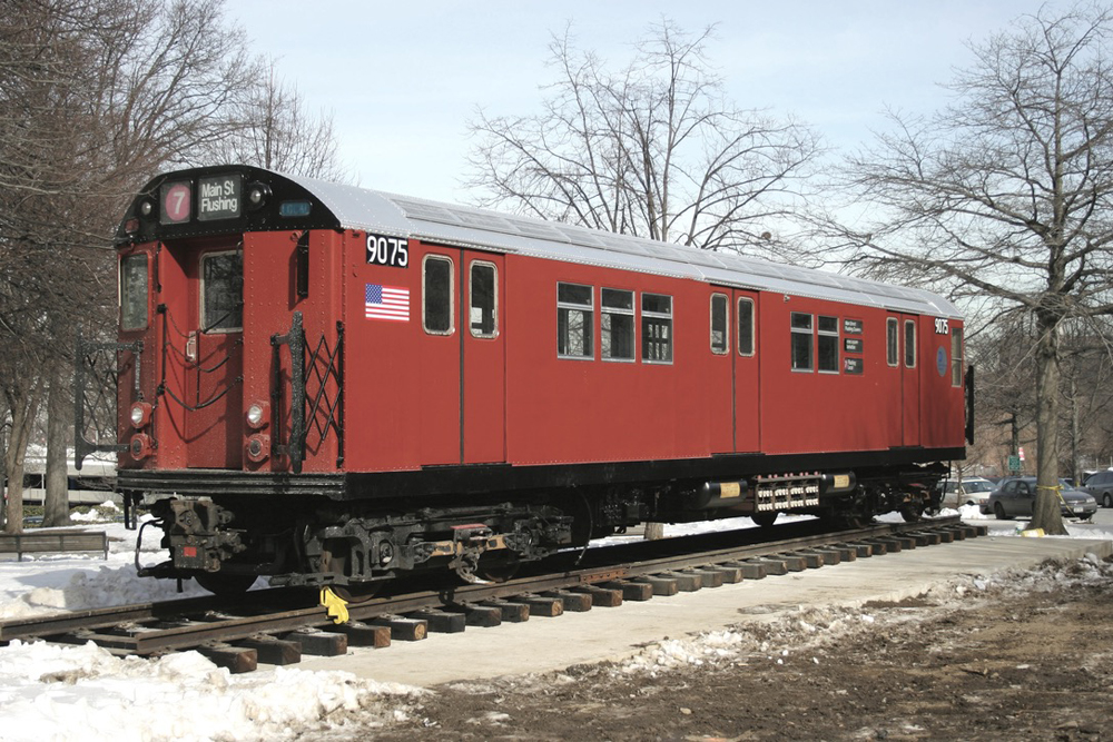 Red subway car on display on short section of track in park