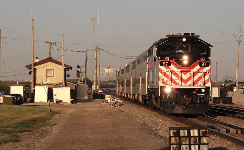 Commuter train passes interlocking tower in golden afternoon light