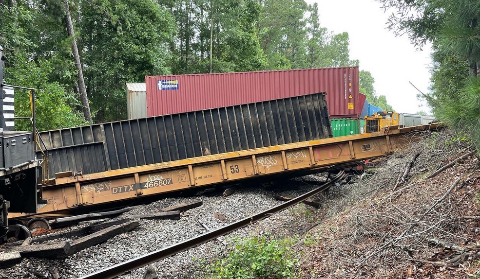 Derailed container cars with yellow switcher visible in background