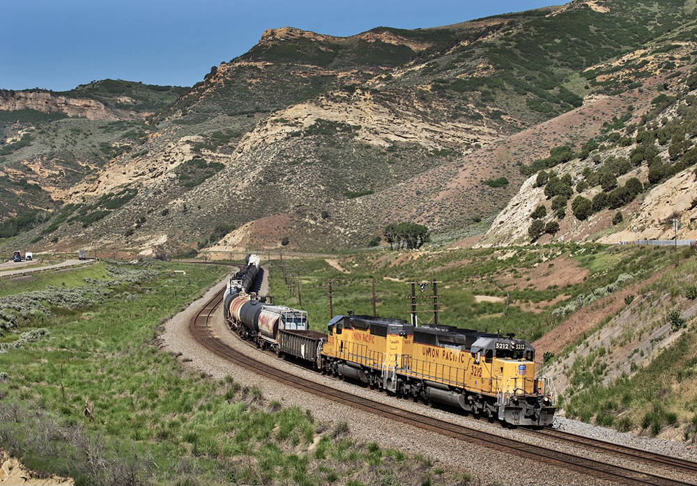 Freight train with two yellow locomotives rounds curve
