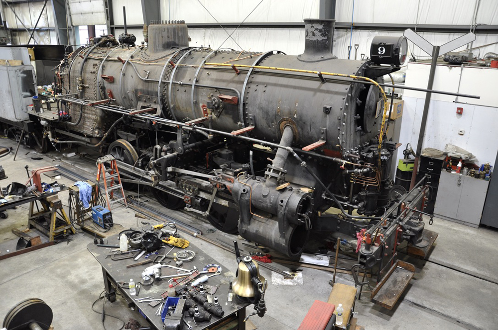 Steam locomotive undergoing work in shop building