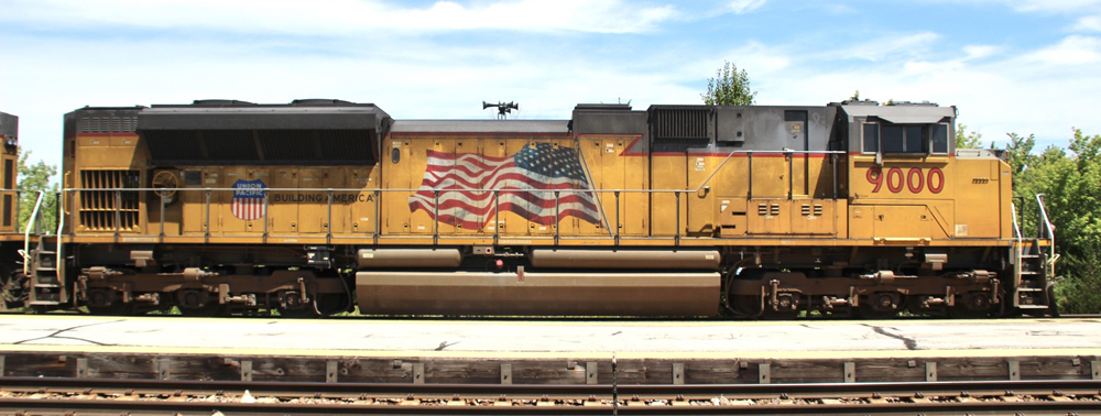 Side view of yellow locomotive with large American flag decal
